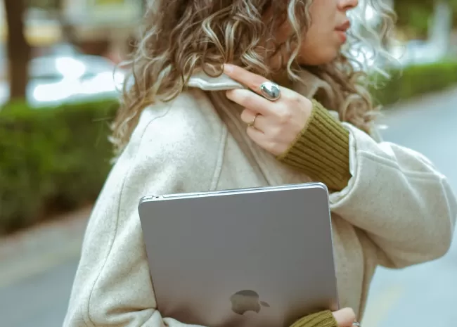 Foto van vrouw met laptop onder haar rechterarm.